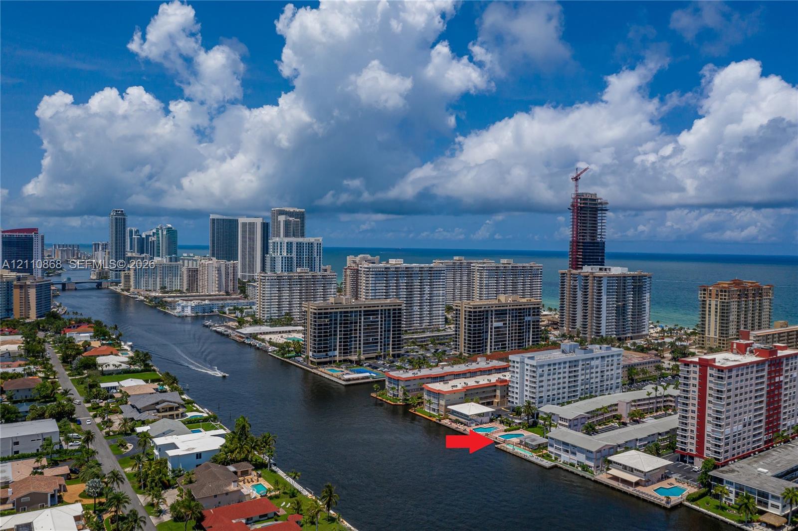 Waterfront complex featuring a swimming pool, canal access, and urban skyline backdrop