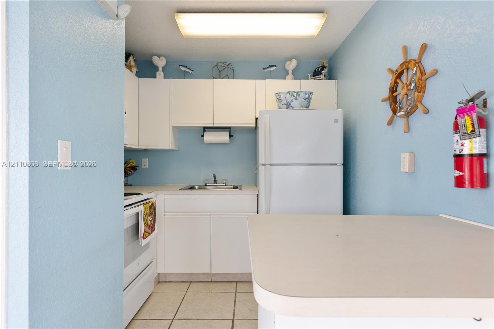 Club house, Kitchen featuring white cabinetry, integrated refrigerator, white range, rectangular basin sink with dual-handle faucet, and tile flooring
