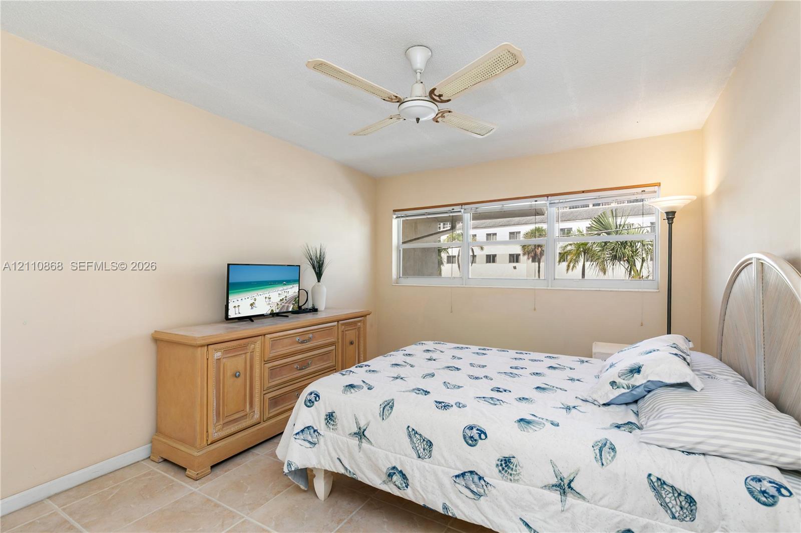 Neutral-toned walls, tile flooring, multi-pane windows, and a ceiling fan with integrated lighting