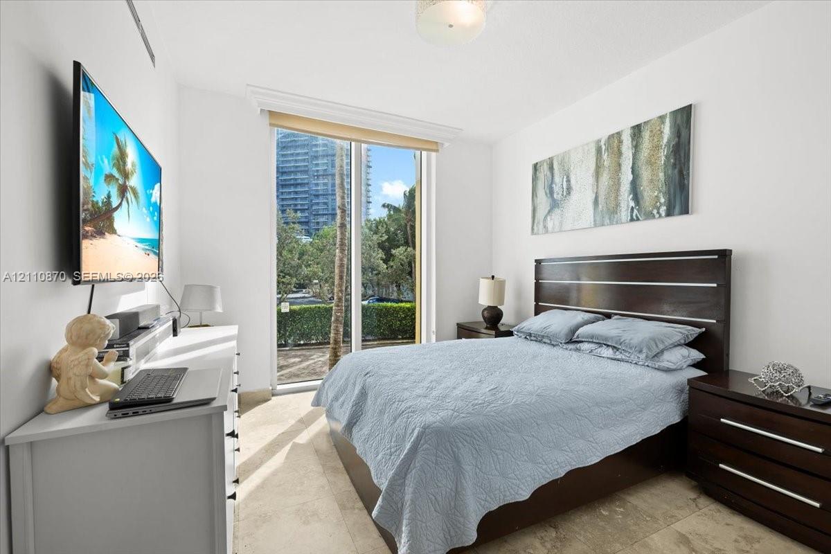Floor-to-ceiling glass door with window treatment and natural stone flooring