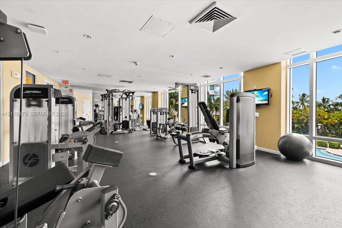 Fitness center featuring floor-to-ceiling windows, rubberized flooring, and recessed lighting