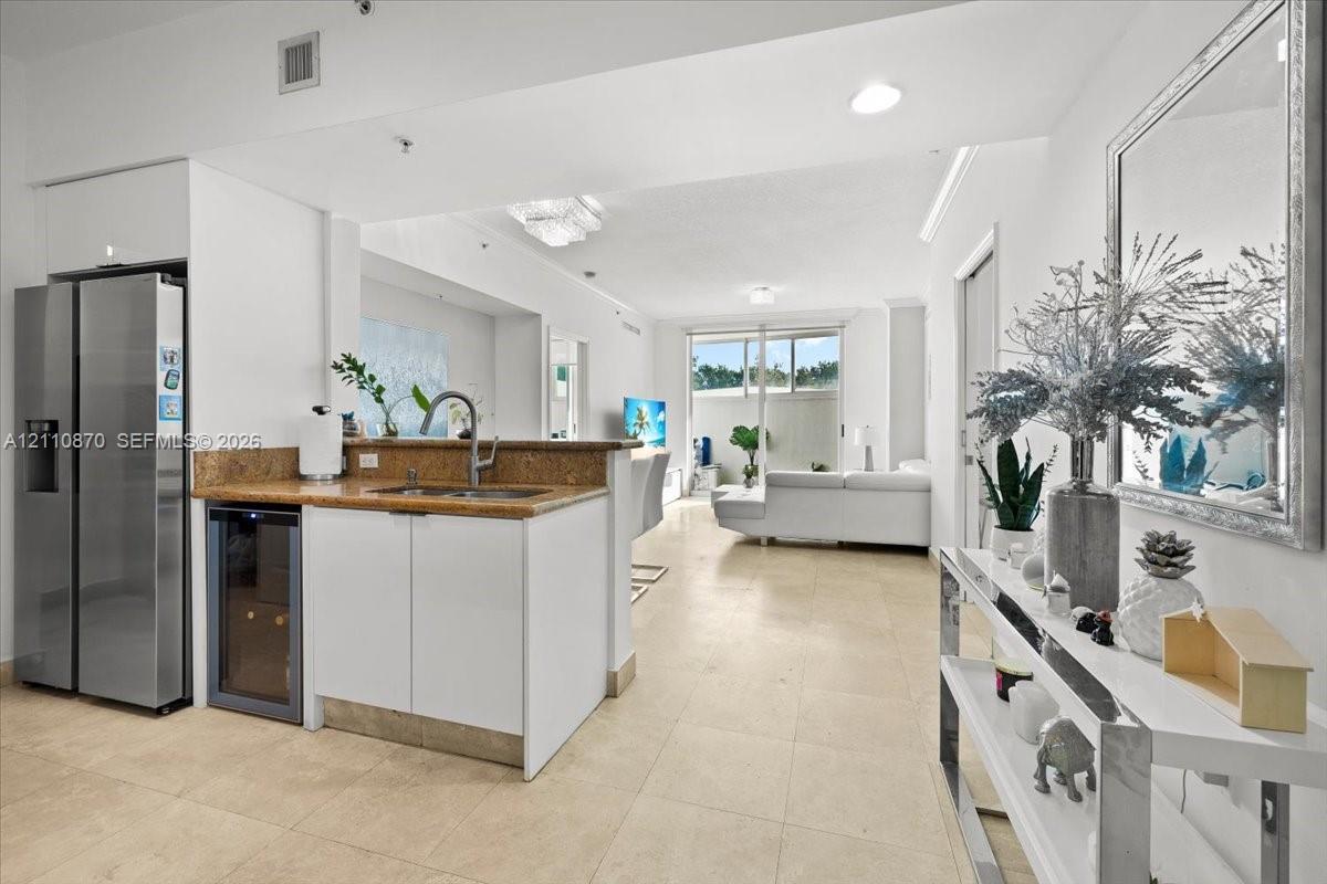 Kitchen area featuring stone-finish countertops, stainless steel side-by-side refrigerator, under-counter wine cooler, and tile flooring