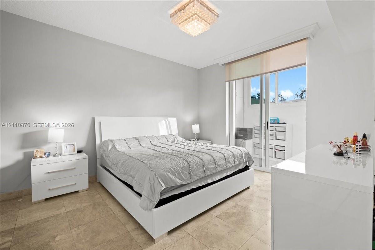 Neutral-toned space featuring large-format tile flooring, a geometric crystal ceiling fixture, and a sliding glass door providing external access