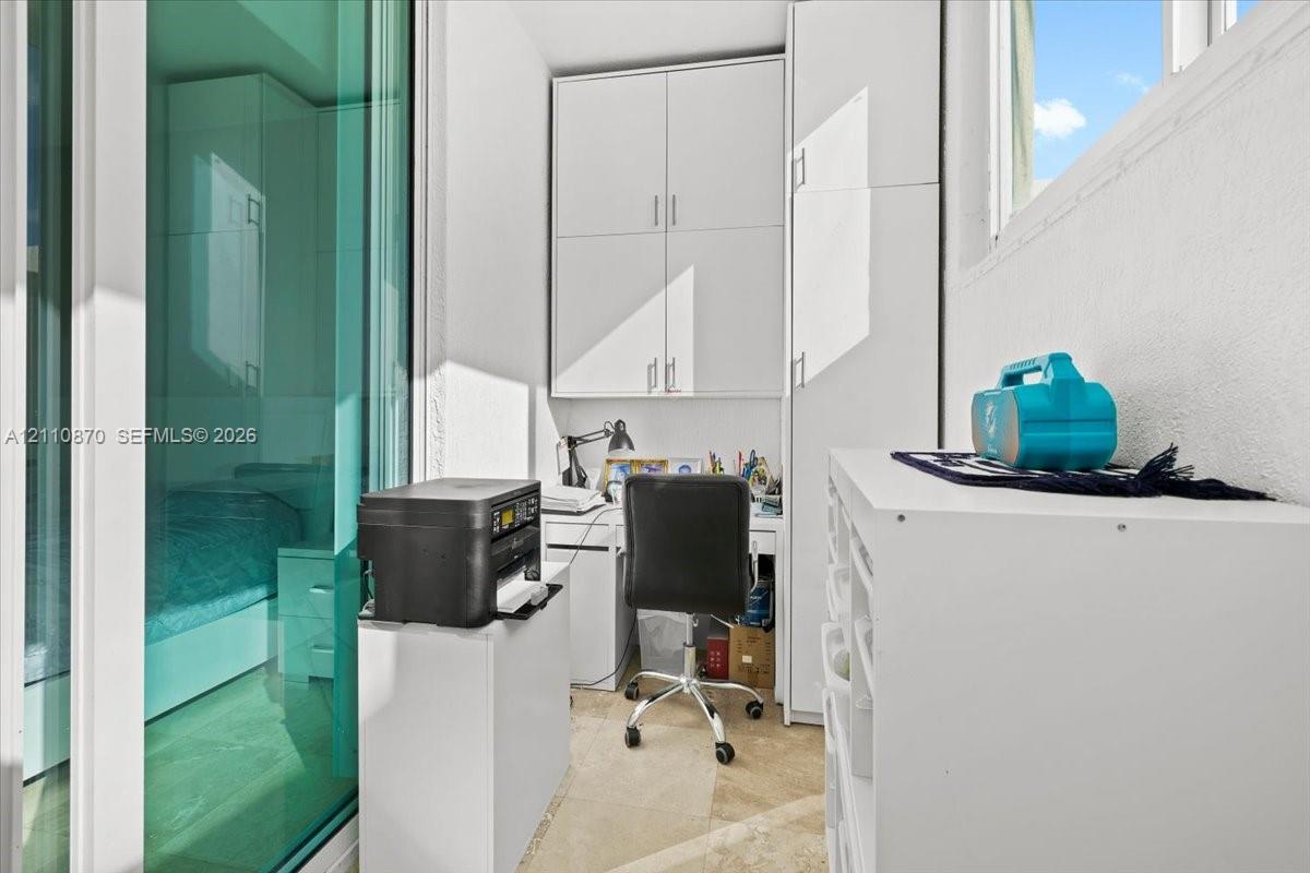 Built-in floor-to-ceiling white cabinetry, tile flooring, and sliding glass panel door