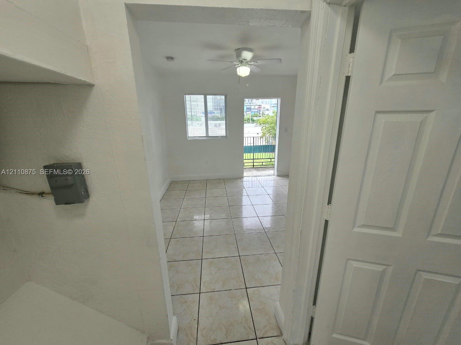 Interior space featuring ceramic tile flooring, a central ceiling fan with integrated lighting, and a glass-paneled exterior door