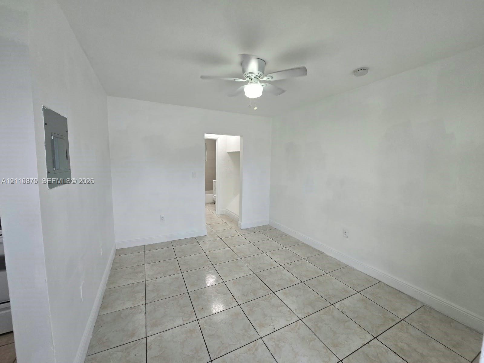 Neutral-toned square tile flooring, white wall finishes, and a central ceiling fan with an integrated light fixture