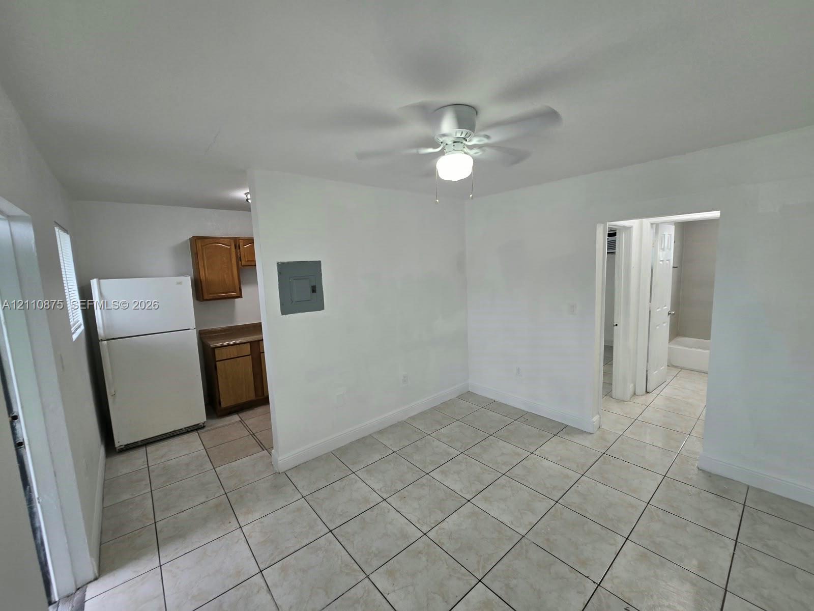 Interior space featuring tile flooring, ceiling fan with integrated lighting, and white cabinetry
