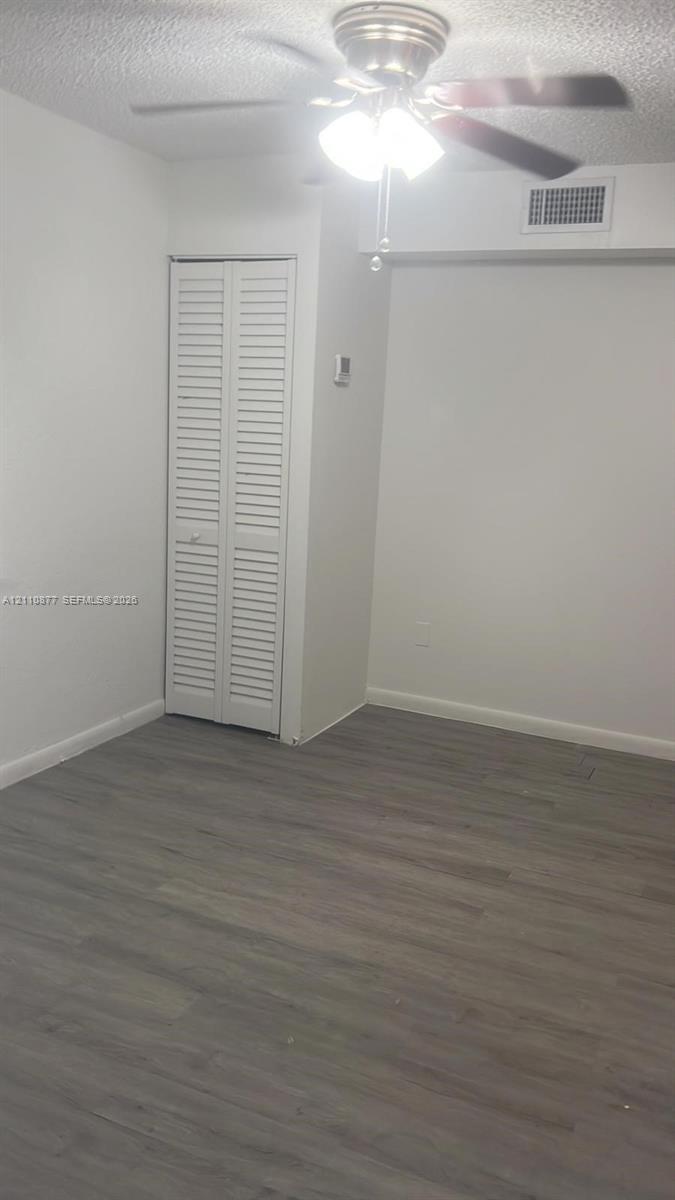 Interior space featuring wood-finish flooring, a white bi-fold closet door, and a ceiling fan with integrated lighting