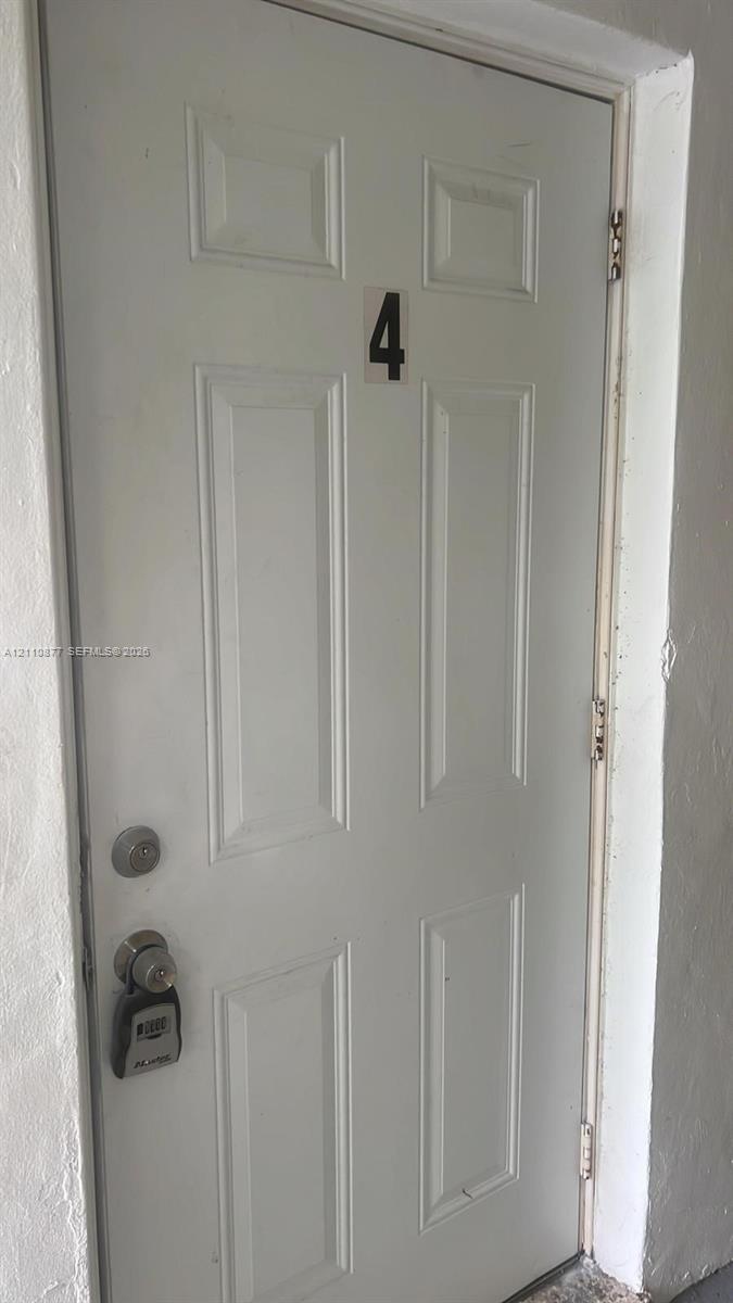 White six-panel entry door featuring a dual-lock system and door-mounted number plate