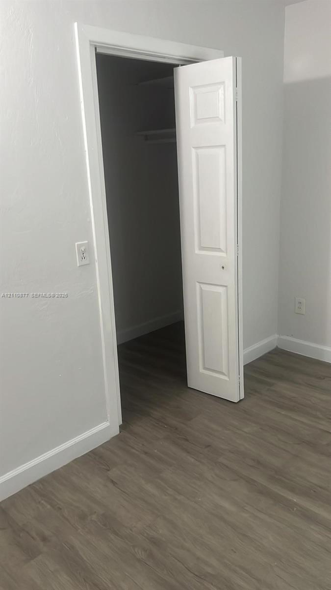 Wood-finish flooring, neutral wall tones, and a closet featuring a three-panel door with interior shelving