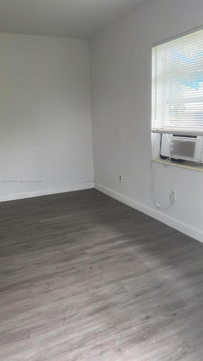 Neutral wall tones, wood-finish flooring, window with integrated blinds, and built-in wall-mounted air conditioning unit