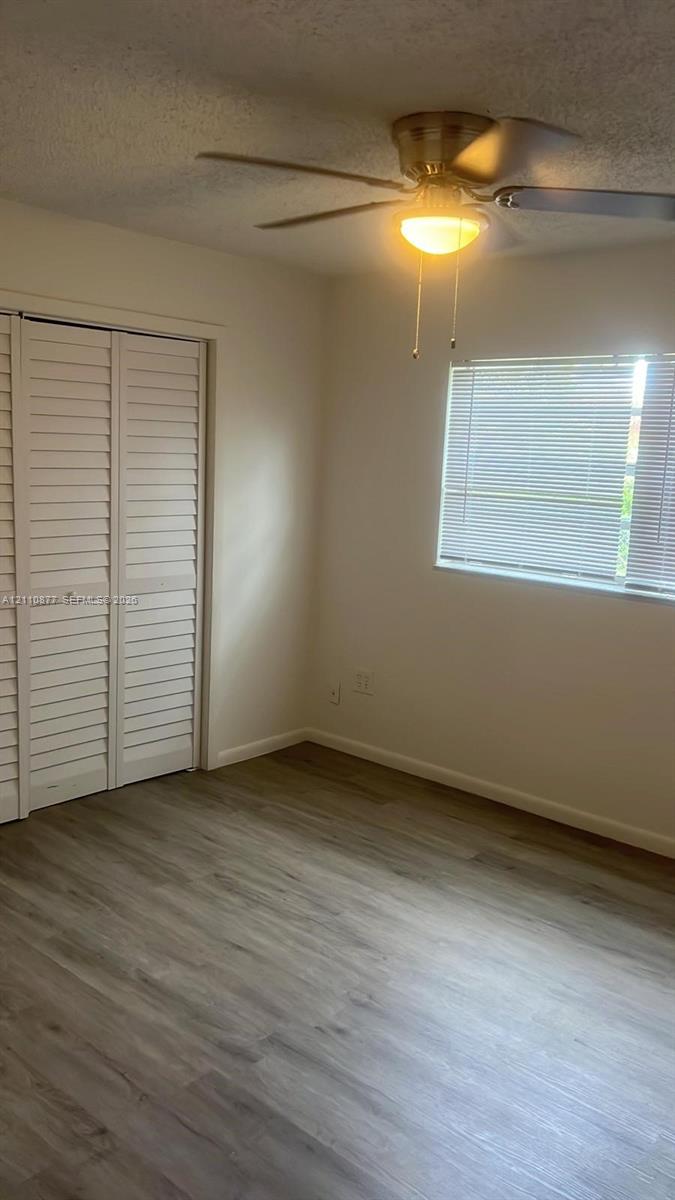 Wood-finish flooring, ceiling fan with integrated lighting, window blinds, and dual bi-fold closet doors