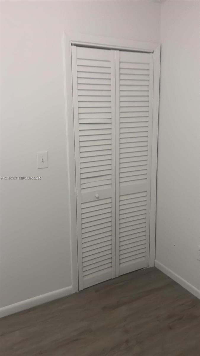White louvered bifold closet doors with wood-finish flooring