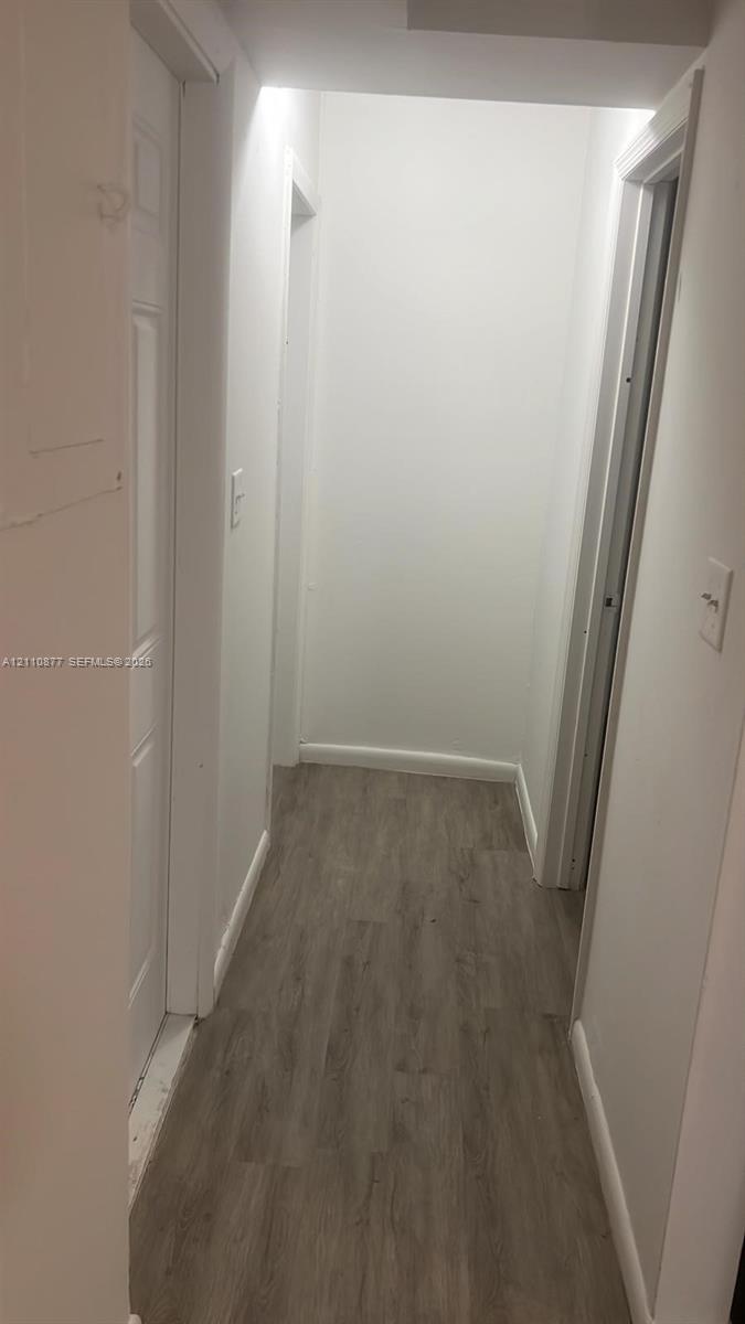 Hallway featuring white interior doors and wood-finish flooring