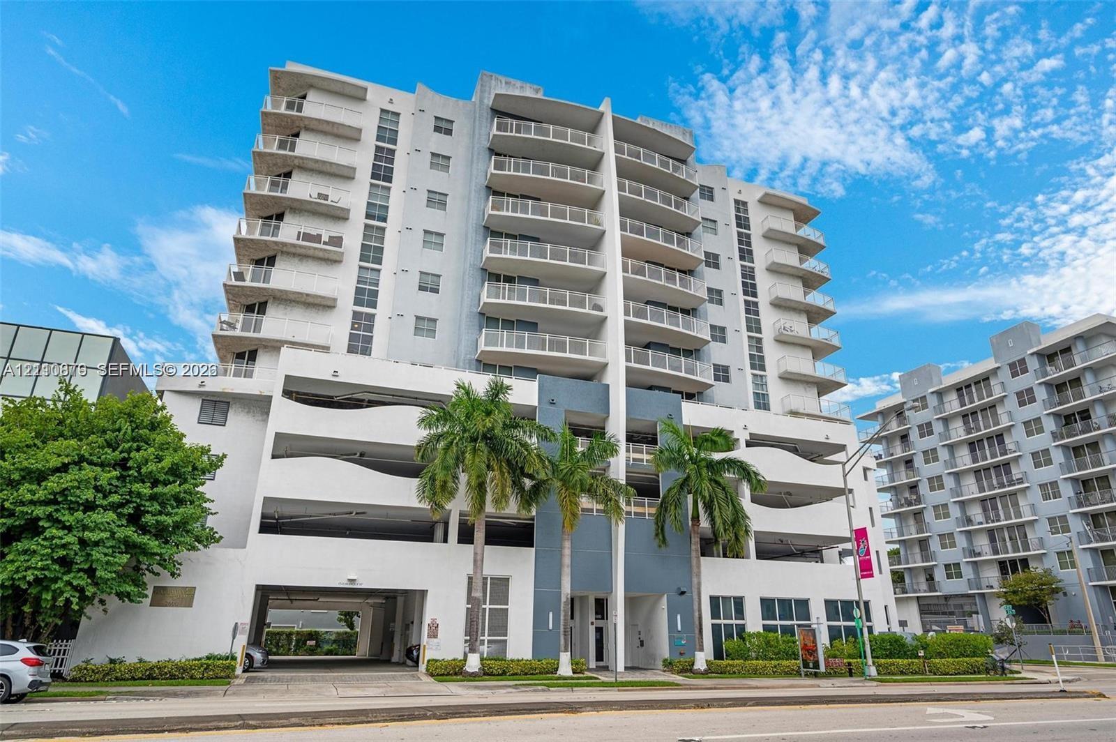 High-rise residential exterior featuring private balconies, integrated parking structure, and palm tree landscaping High-rise residential exterior featuring private balconies, integrated parking structure, and palm tree landscaping