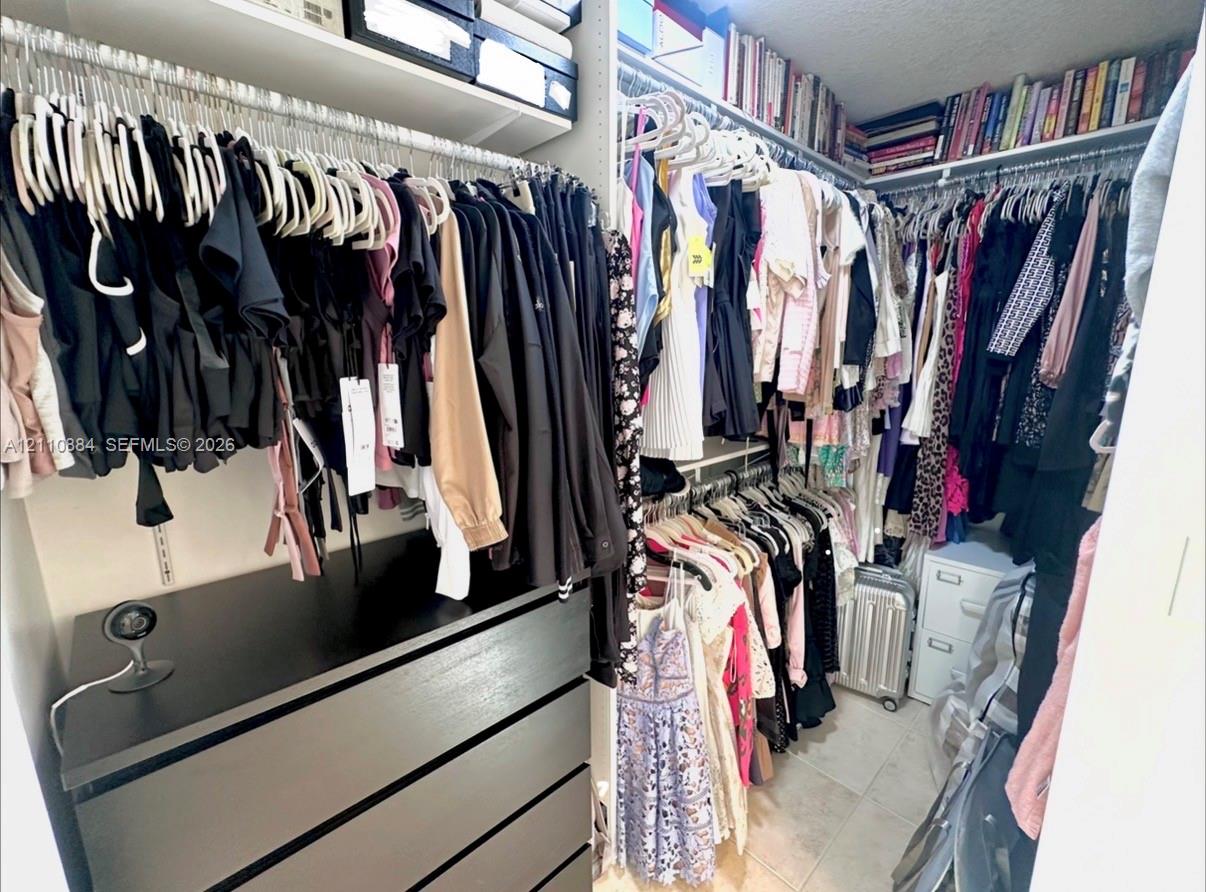Walk-in closet featuring floor-to-ceiling custom shelving, tiered hanging rods, and integrated drawer storage