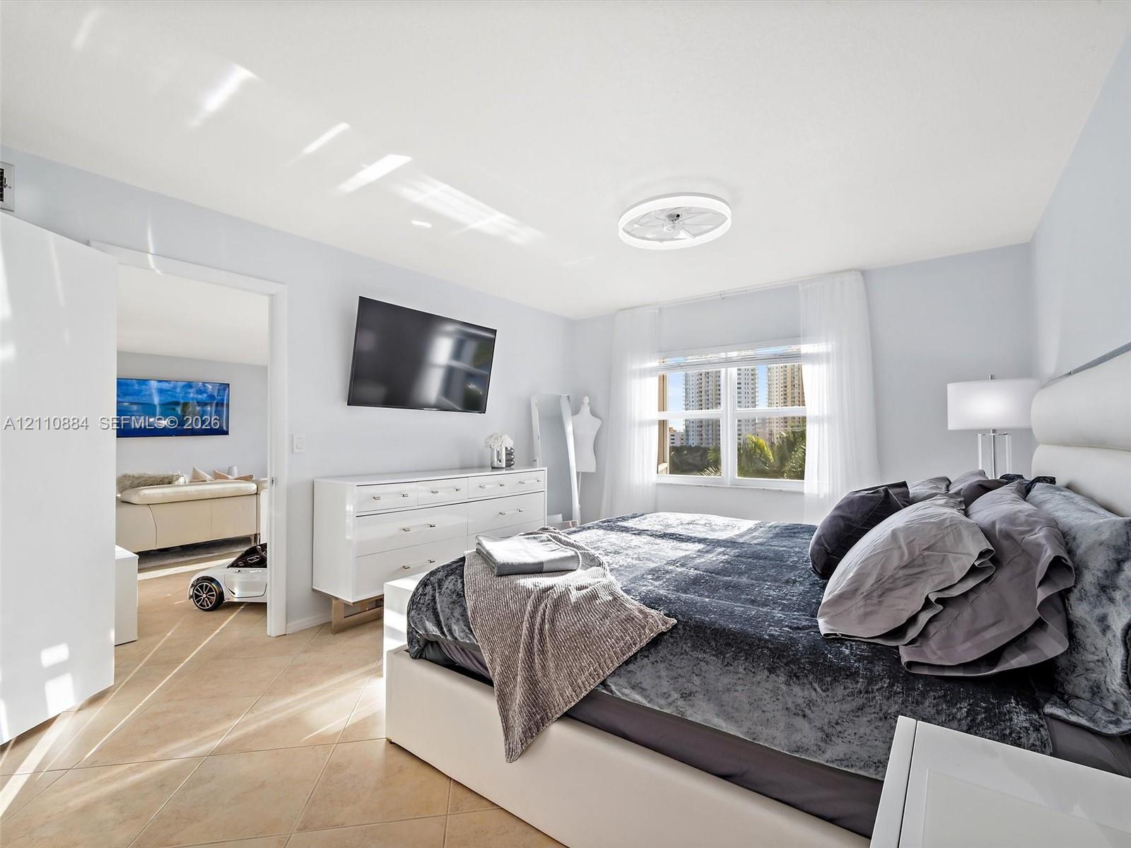 Neutral-toned tile flooring, recessed ceiling lighting with integrated fan, and brand new impact rated oversized window with exterior exposure, water, lake, golf course and tropical oasis views