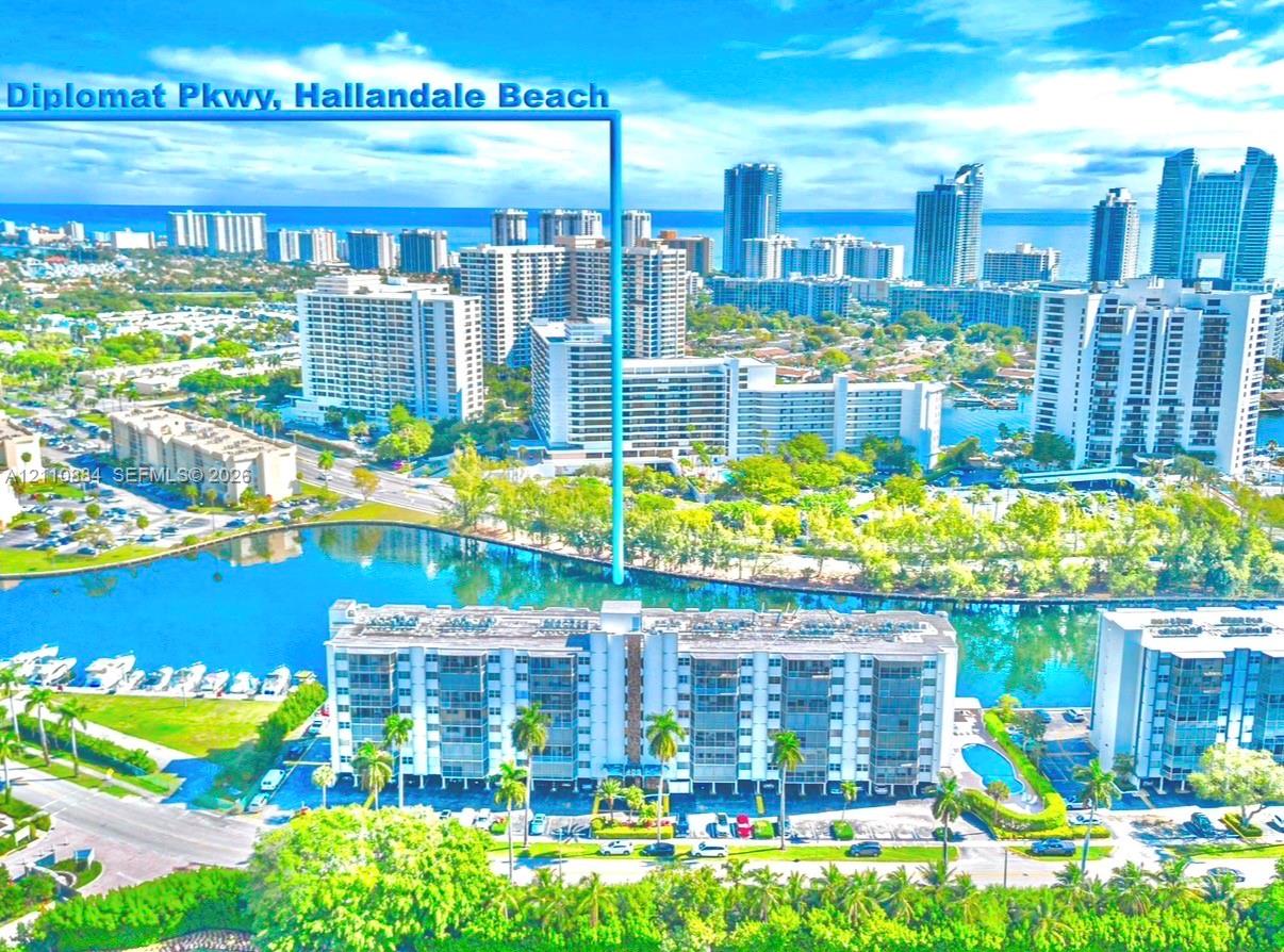 Aerial perspective of Diplomat Parkway featuring waterfront proximity, expansive waterway frontage, mature palm trees, and multi-story residential architecture