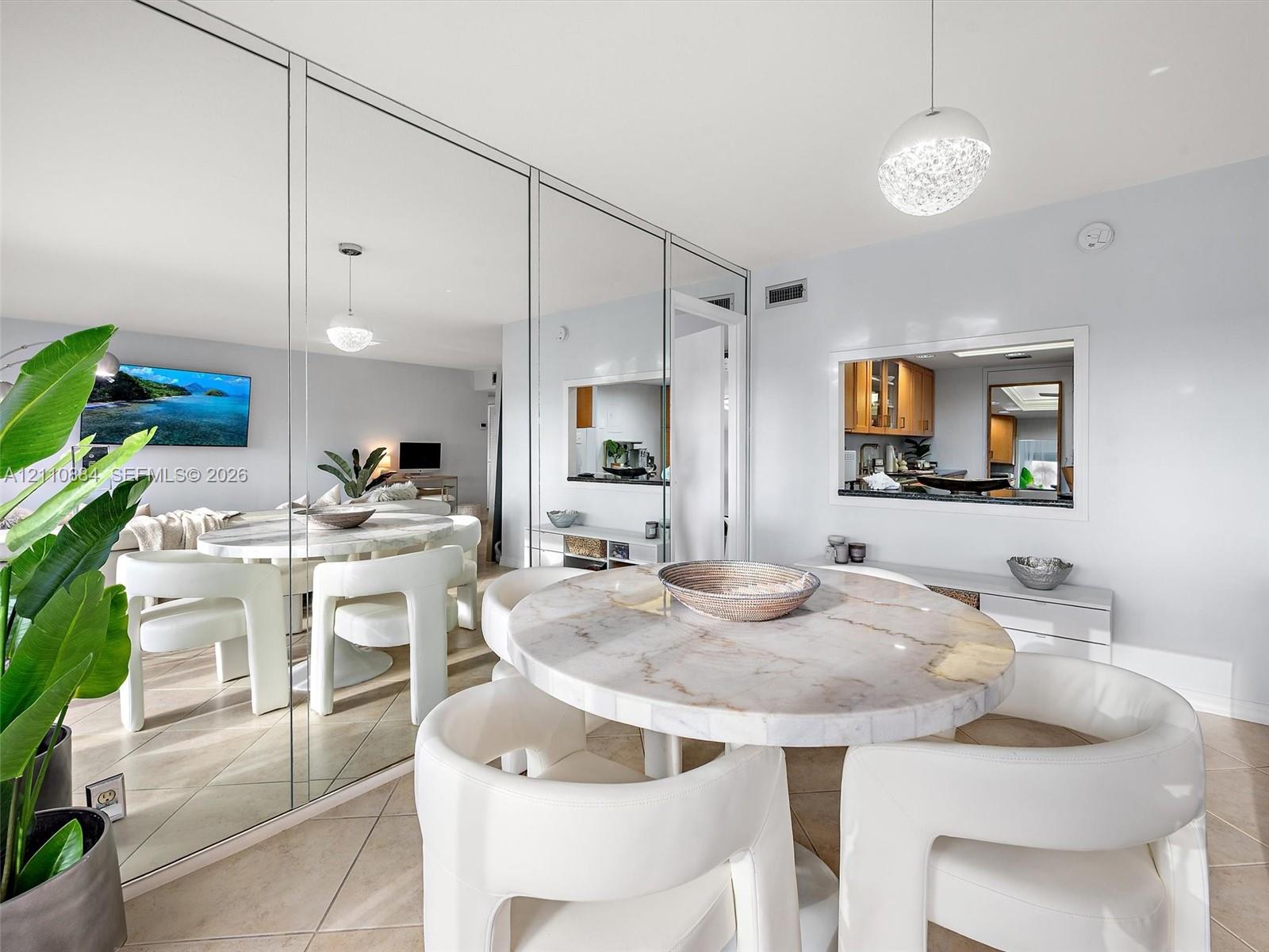 Full-wall mirrored accent, tile flooring, built-in kitchen pass-through window, and contemporary spherical pendant lighting