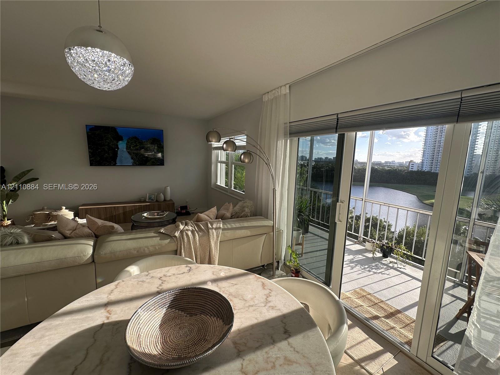 Living area featuring sliding glass doors to a balcony, floor-to-ceiling windows, and a decorative dome pendant light