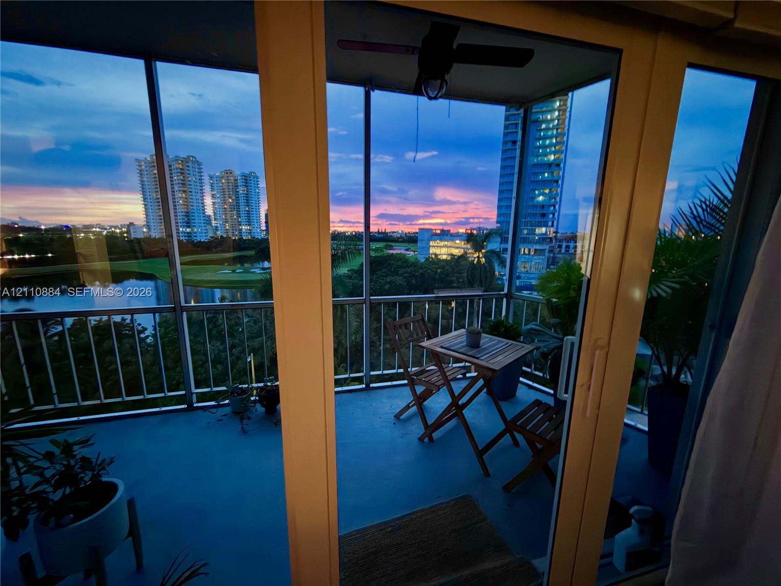 Screened-in balcony featuring sliding glass door access, metal railings, and overhead ceiling fan