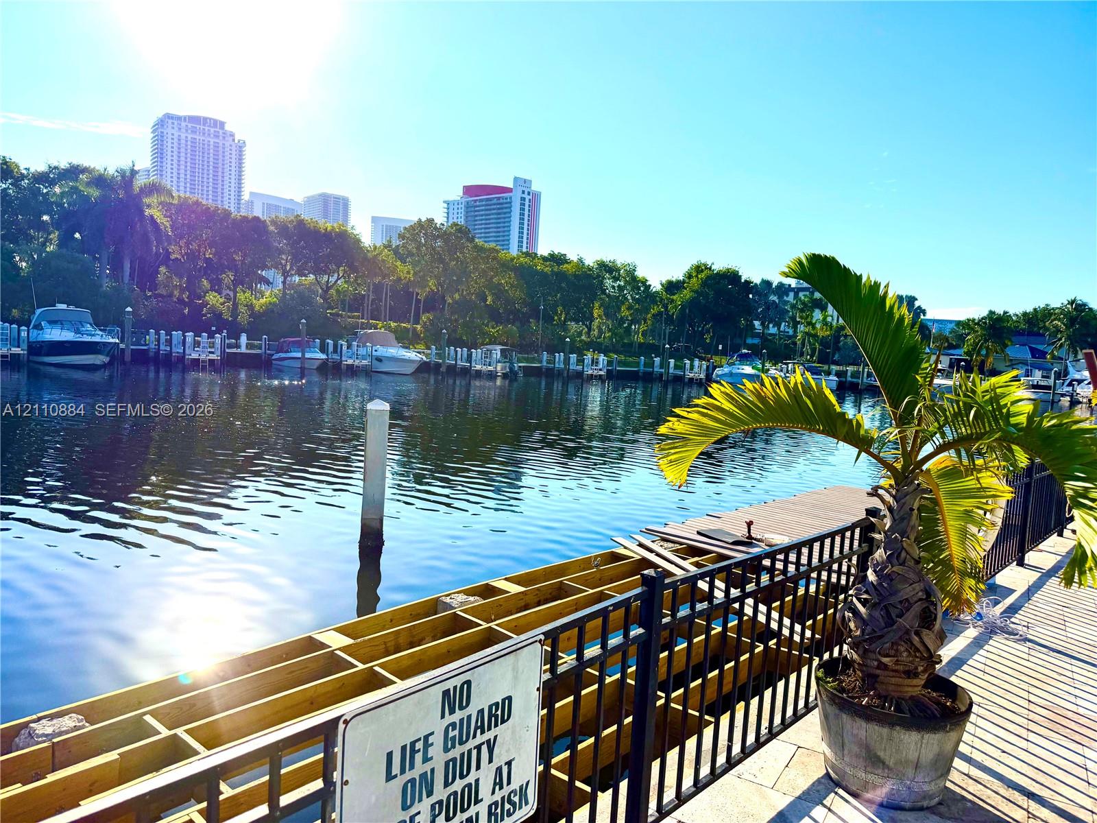 Waterfront bulkhead with timber framing, paved walking path, and black metal perimeter fencing