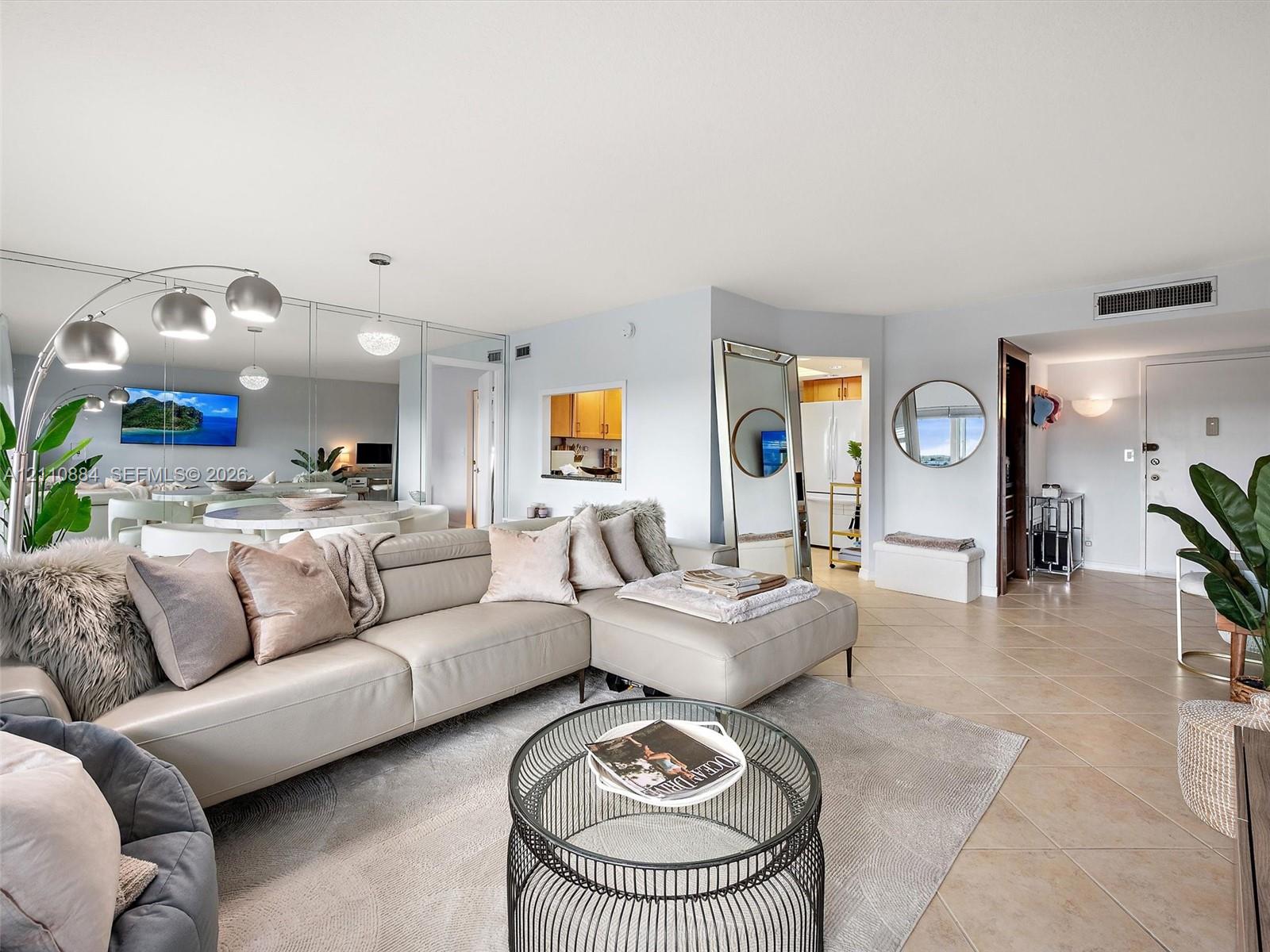 Living area featuring large-format ceramic tile flooring, mirrored wall paneling, and an architectural interior pass-through window