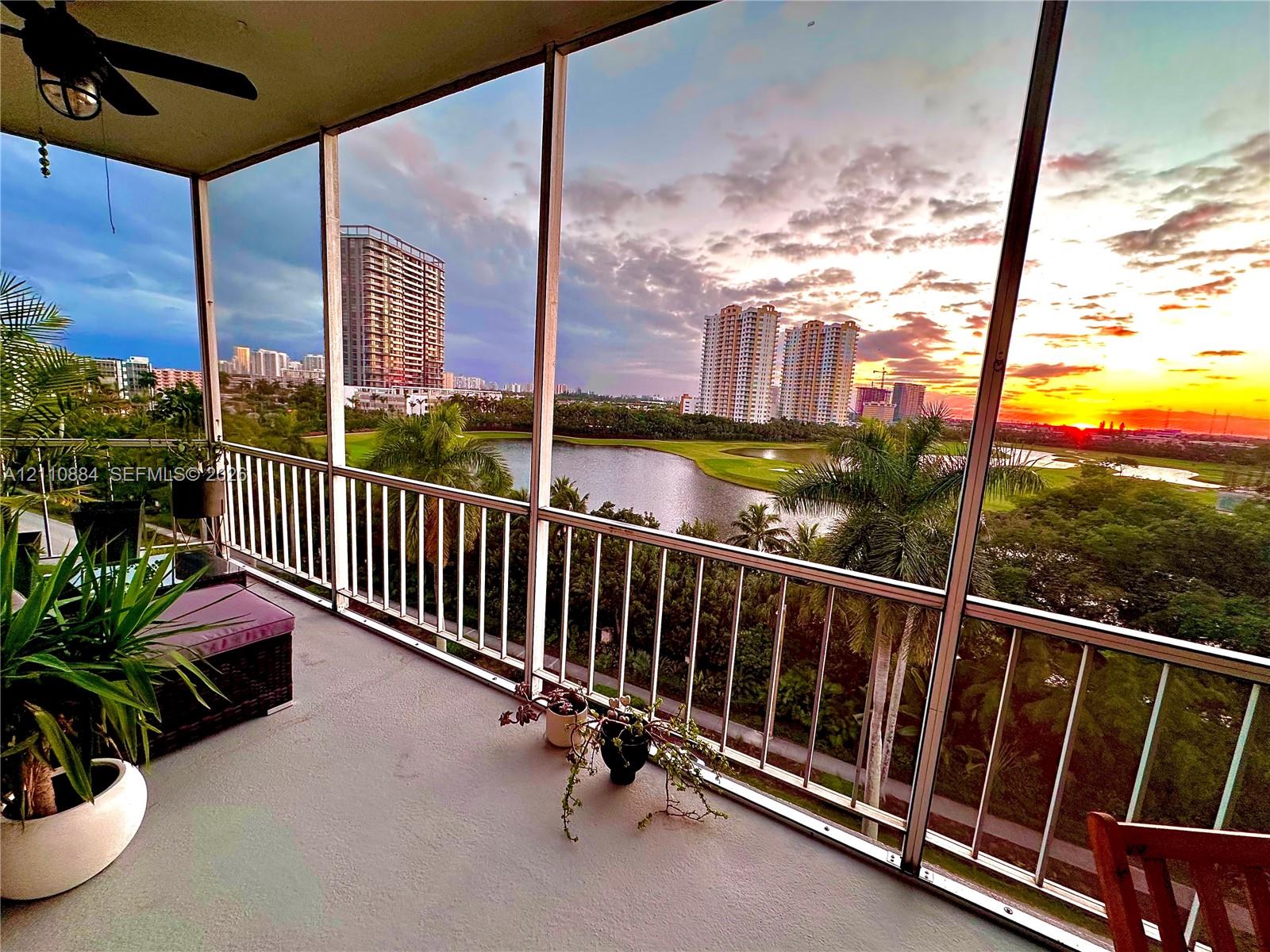 Screened-in balcony featuring white metal railings, a ceiling fan, and concrete flooring Screened-in balcony featuring white metal railings, a ceiling fan, and concrete flooring