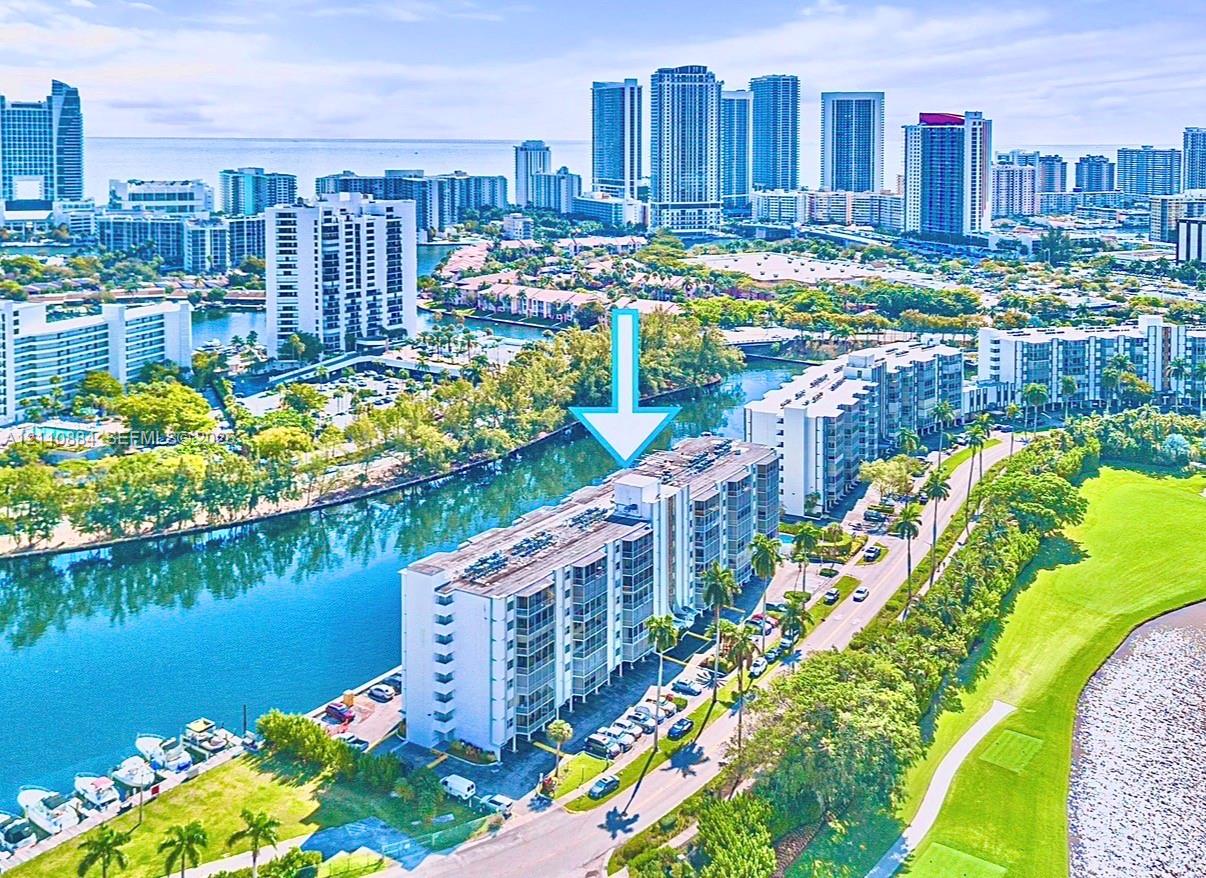 Mid-rise waterfront condominium complex featuring private boat slips, balconies with sliding glass doors, exterior parking, and proximity to green space