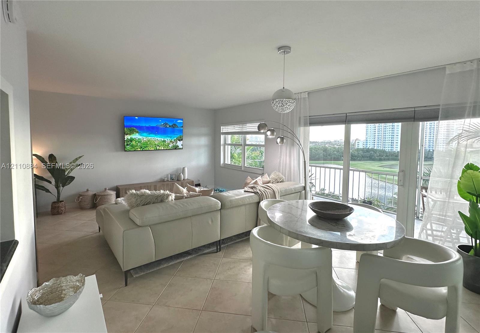 Neutral tile flooring throughout, expansive floor-to-ceiling glass sliding doors, polished pendant lighting, and multiple windows providing natural illumination