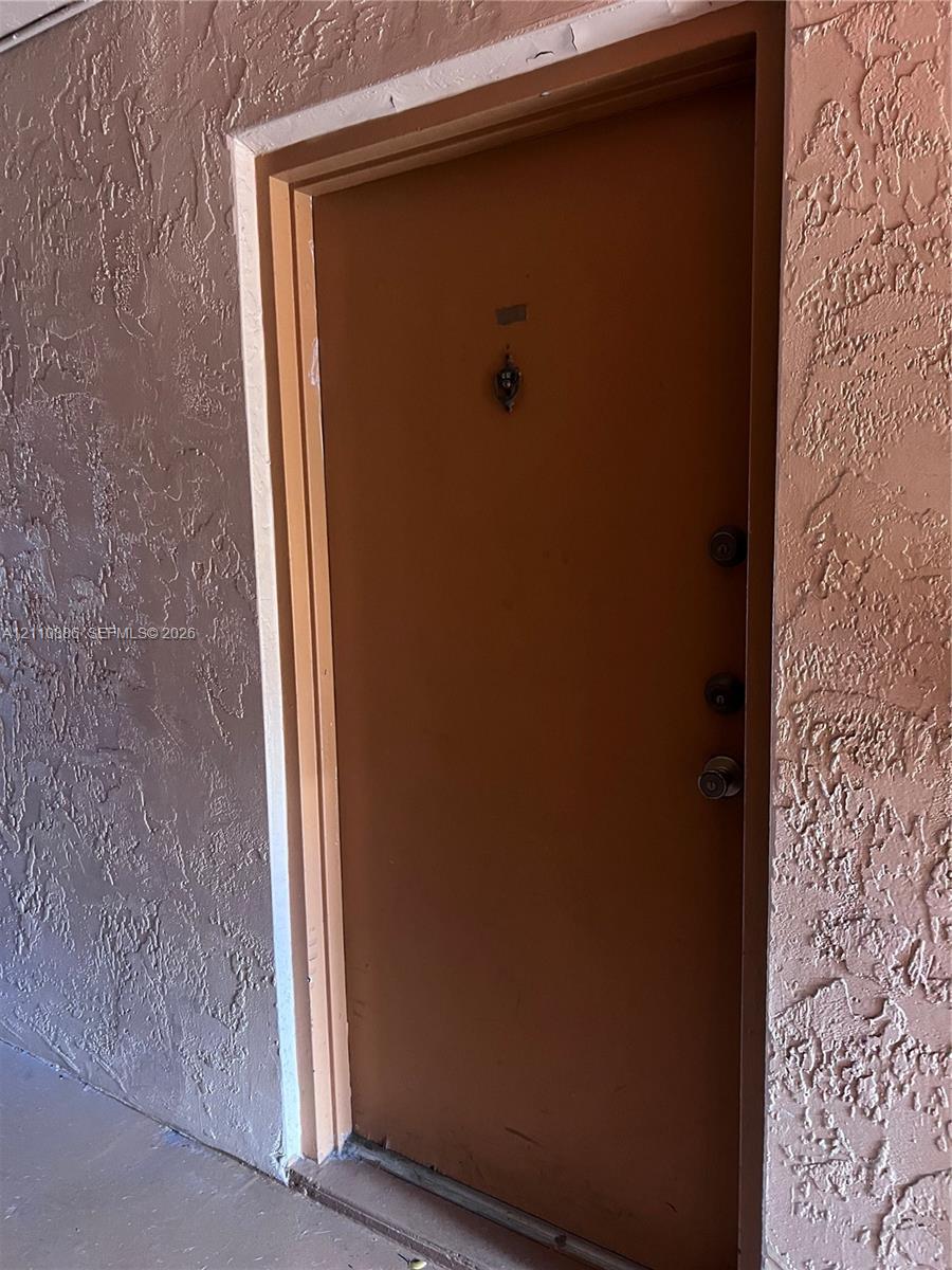 Solid wood-finish door featuring a metal door knocker, dual deadbolt locks, and a metal door handle