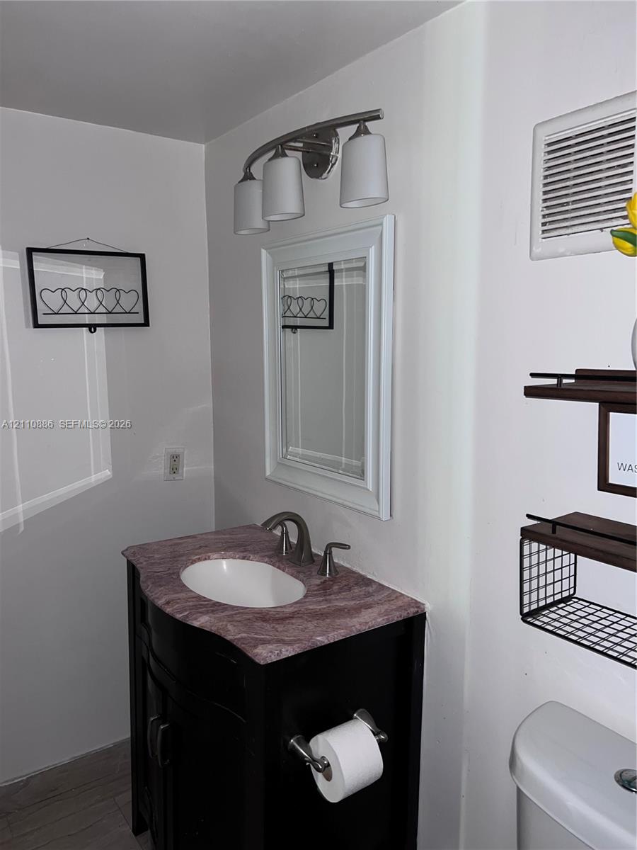 Reach-in closet featuring a white louvered door, interior wire shelving, and tile flooring