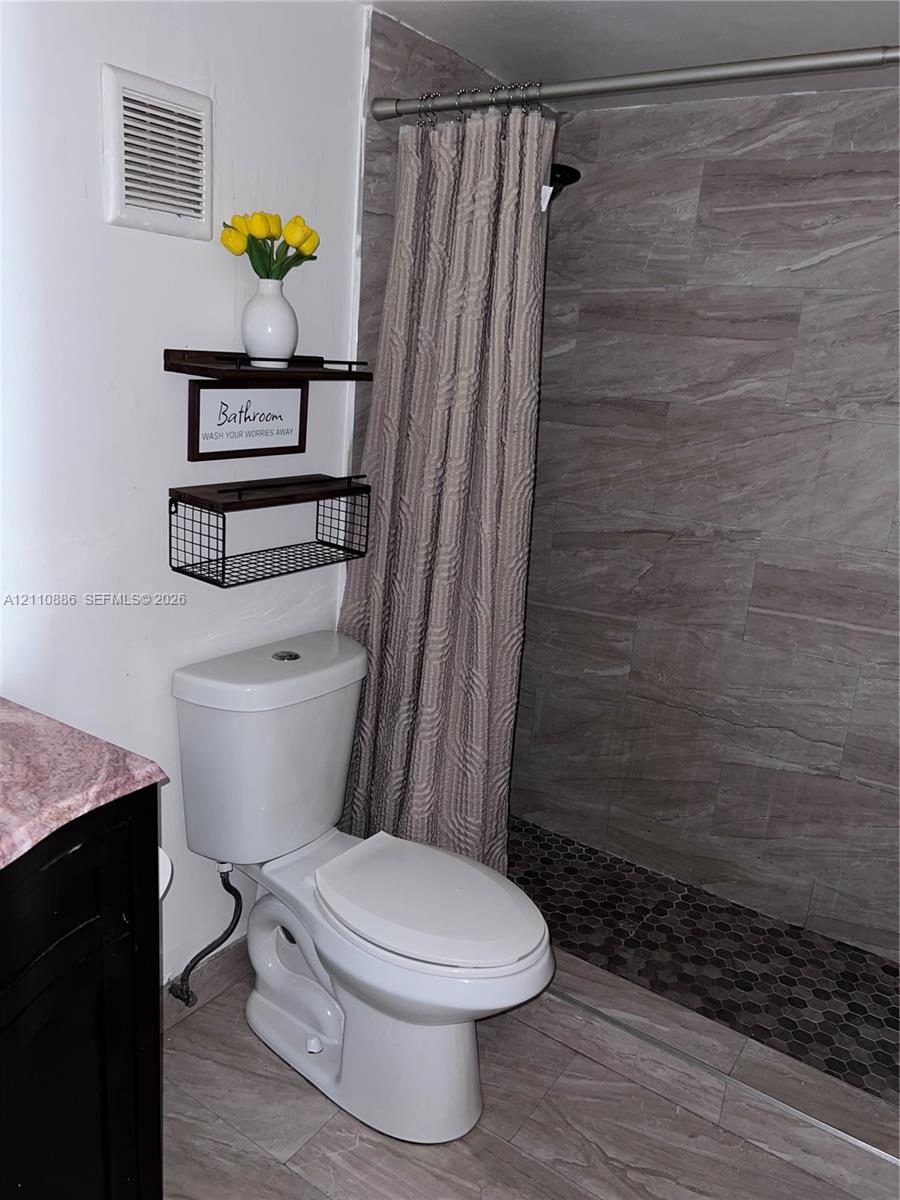 Dark-finish vanity featuring an integrated basin, stone-composite countertop, brushed-nickel faucet, and a three-light wall fixture