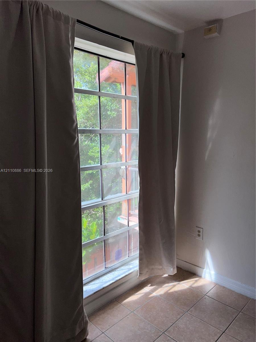 Grid-patterned window with exterior ledge, neutral-toned tile flooring, and solid-colored walls