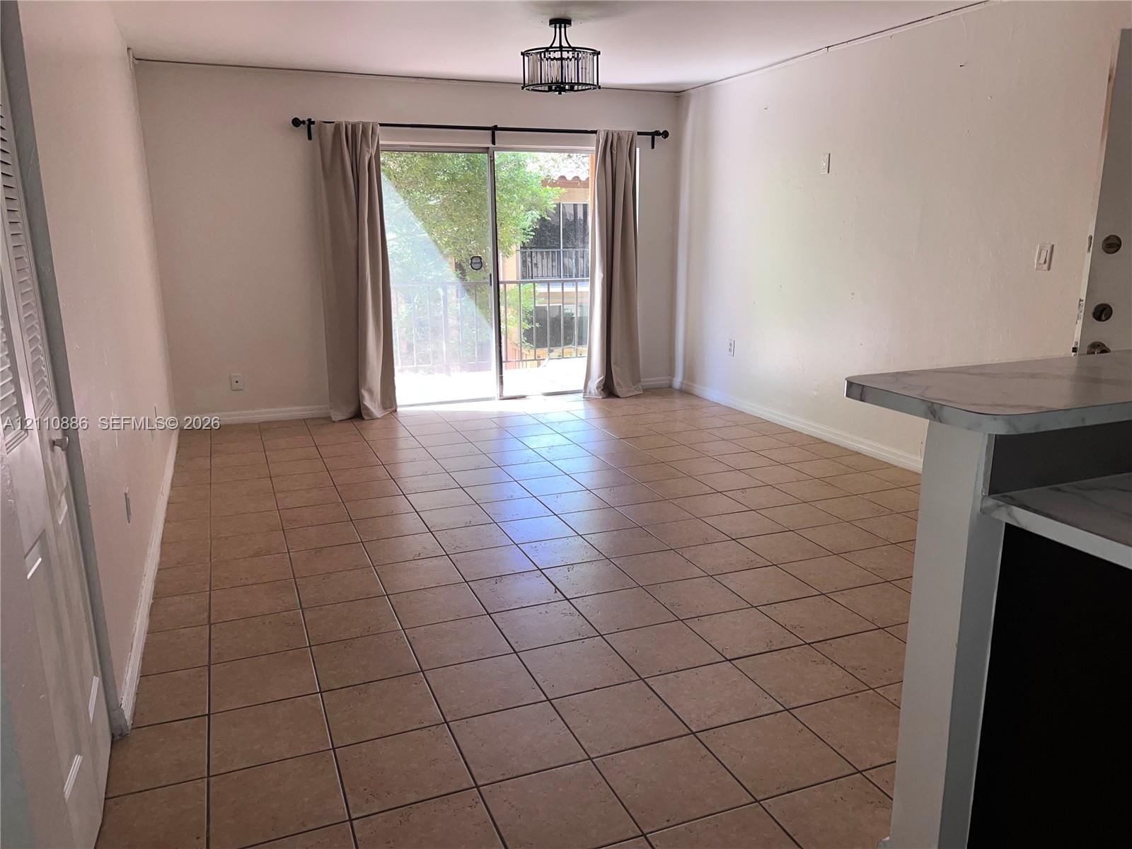 Ceramic tile flooring, sliding glass door, and geometric drum-style ceiling light fixture