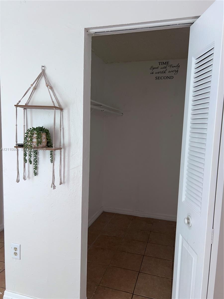 Grid-patterned window with exterior ledge, neutral-toned tile flooring, and solid-colored walls