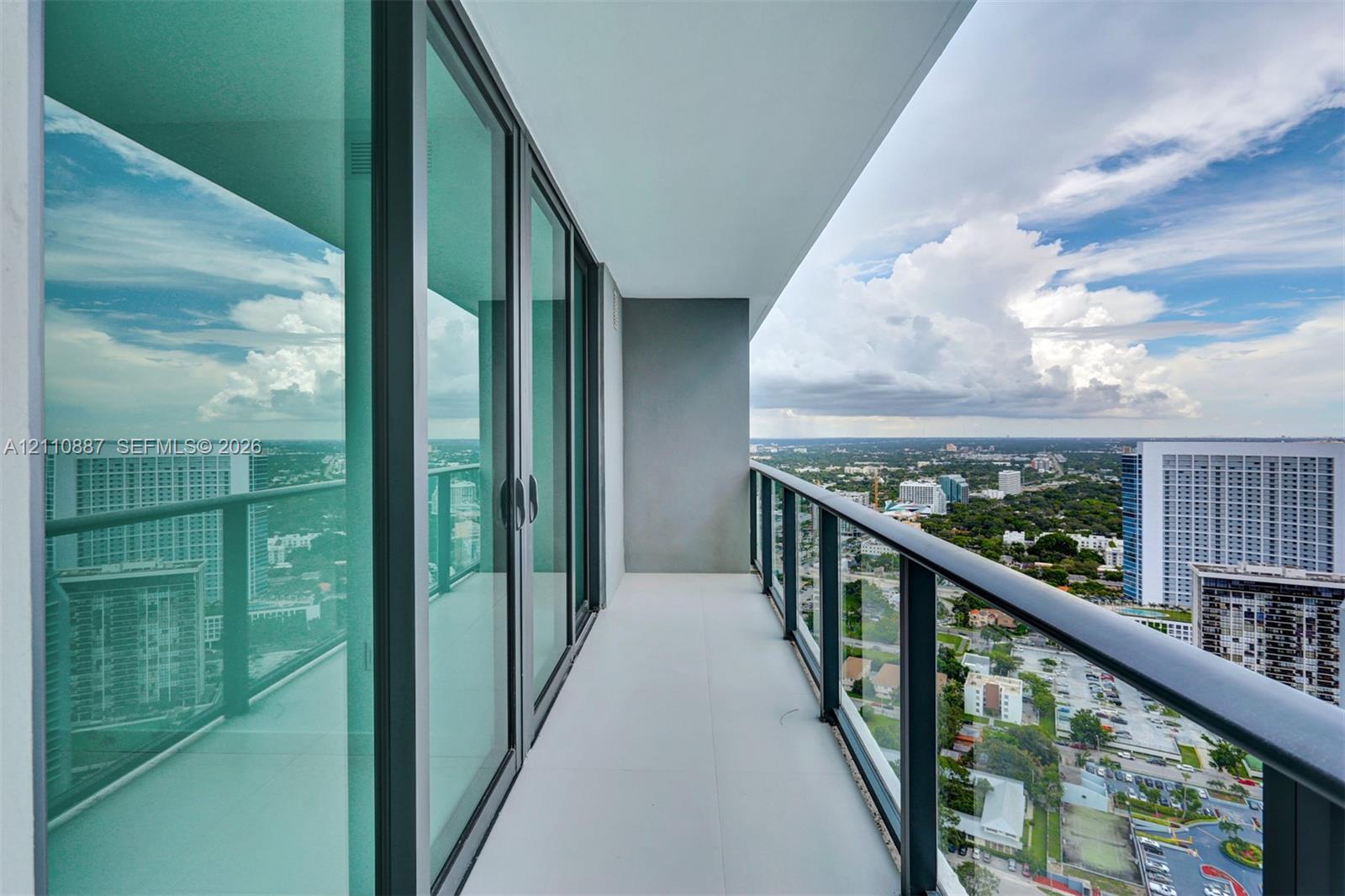 Private balcony featuring floor-to-ceiling glass sliding doors, a metal railing, and neutral tile flooring