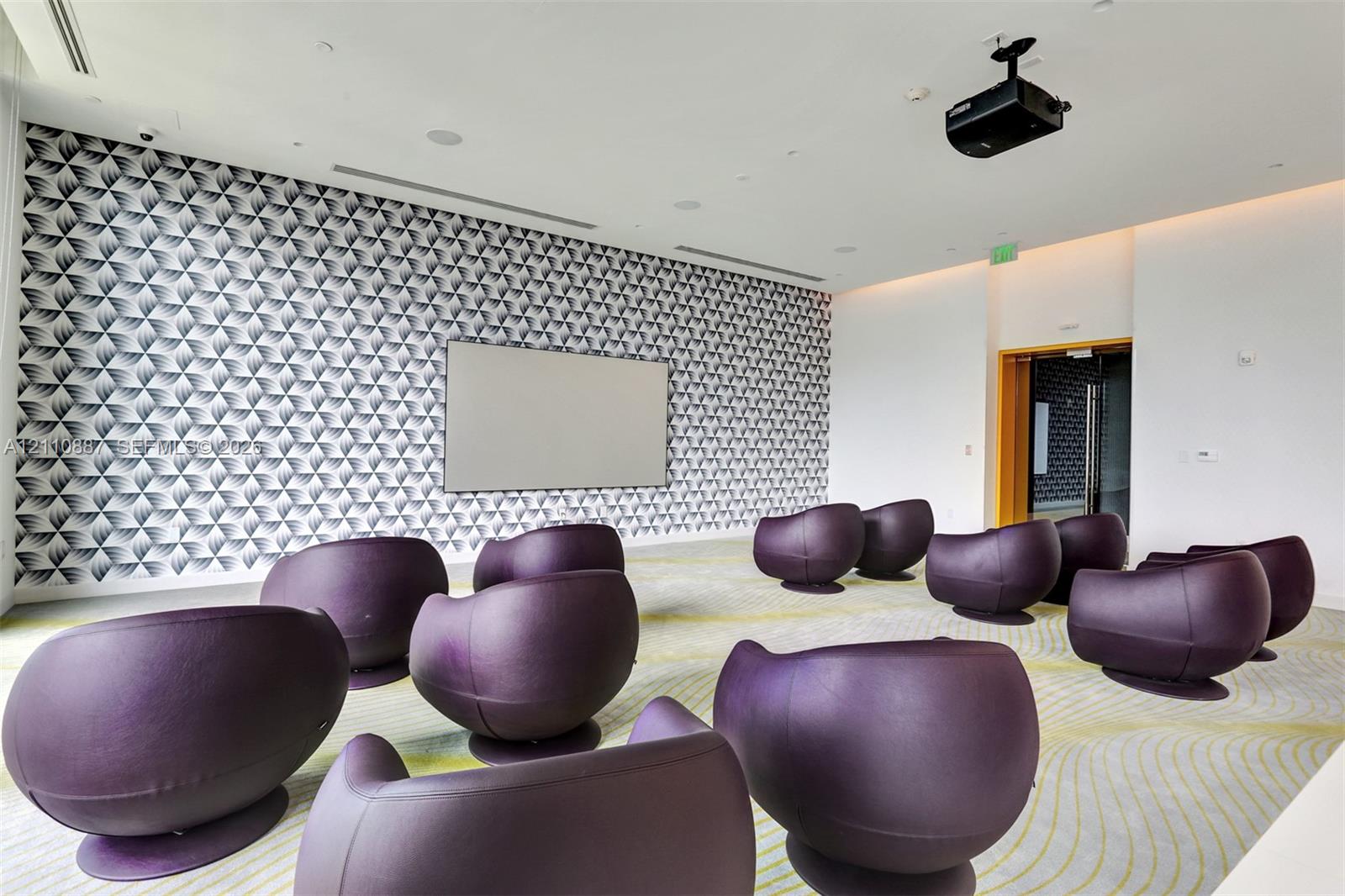 Room featuring a mounted projection screen, ceiling-mounted projector, patterned wall covering, recessed lighting, and integrated sound system speakers