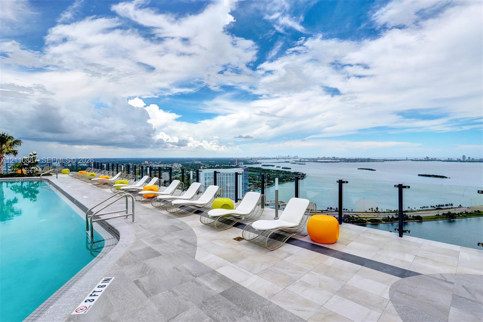 Rooftop swimming pool with tiled decking and glass panel perimeter railing