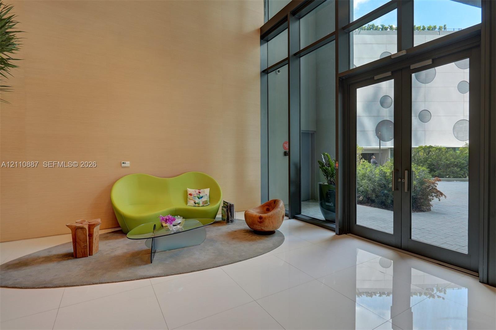Double-height entryway featuring floor-to-ceiling glass paneling, full-height double door entry, and polished large-format tile flooring