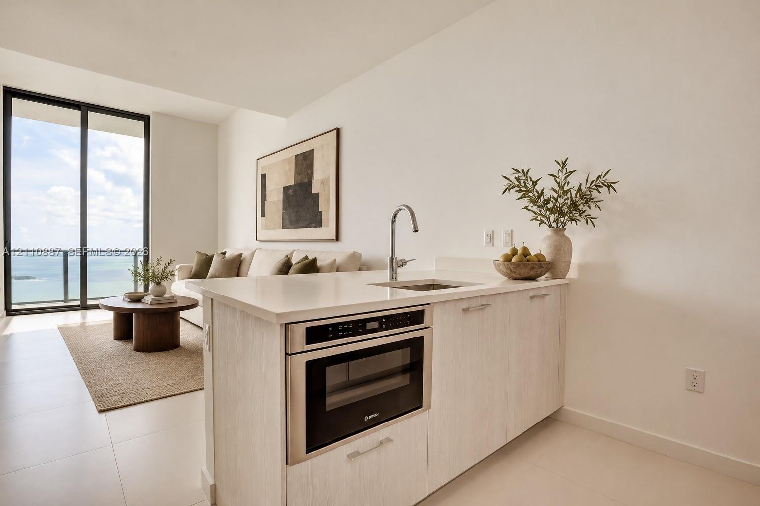 Kitchenette featuring light-finish cabinetry, quartz countertops, an integrated microwave, and a stainless steel undermount sink Kitchenette featuring light-finish cabinetry, quartz countertops, an integrated microwave, and a stainless steel undermount sink