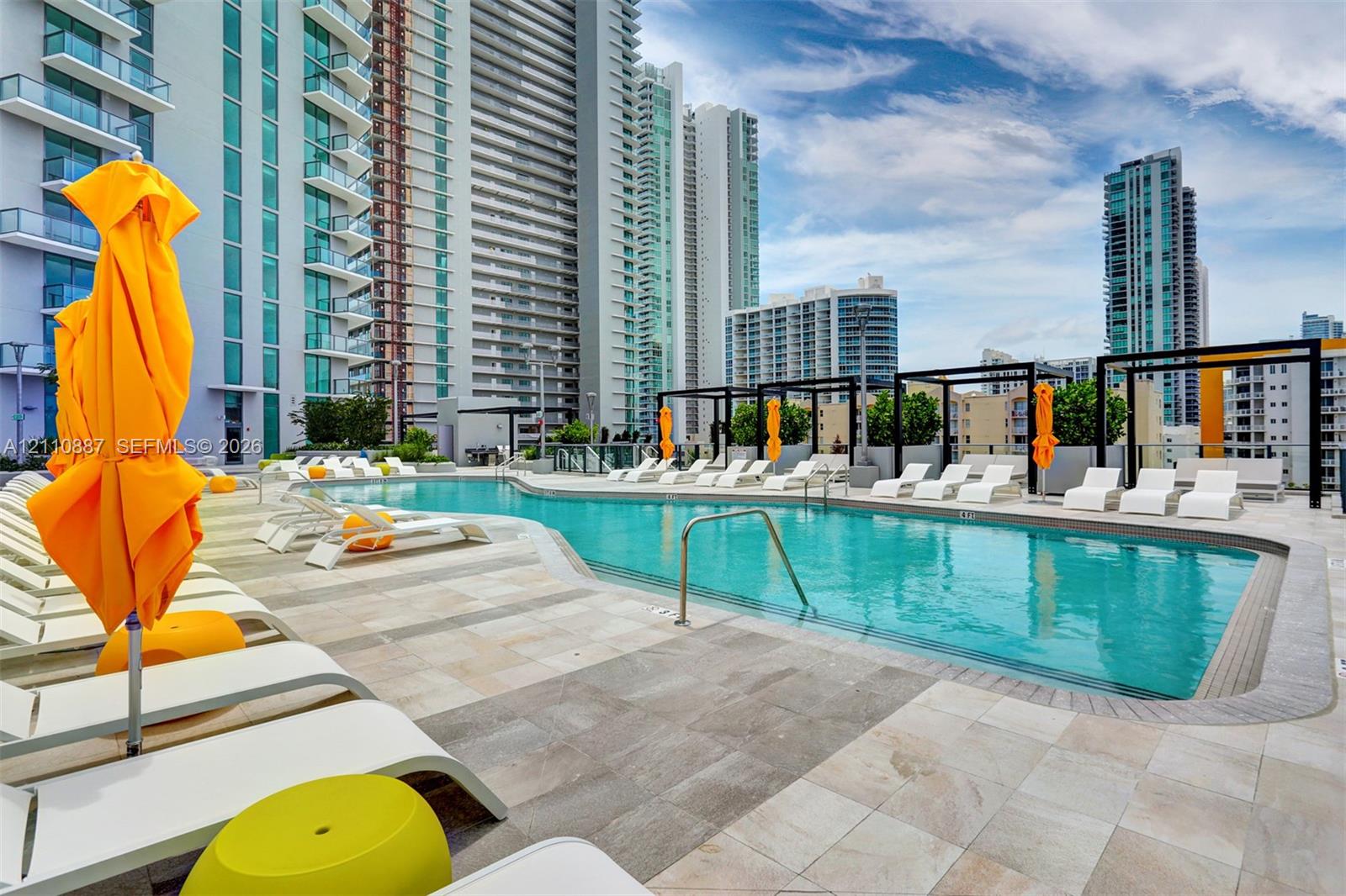 Swimming pool featuring stone tile decking, metal pergola structures, and integrated steel handrails