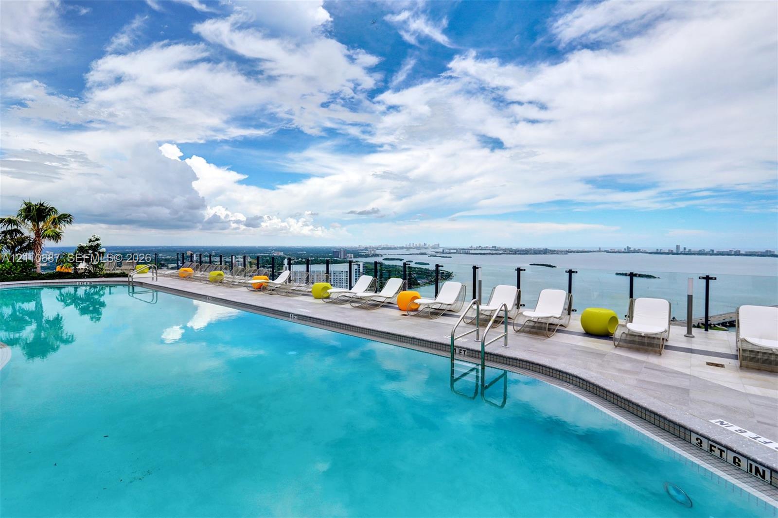Infinity-edge swimming pool featuring a tile surround, metal safety railing, and deep water finish