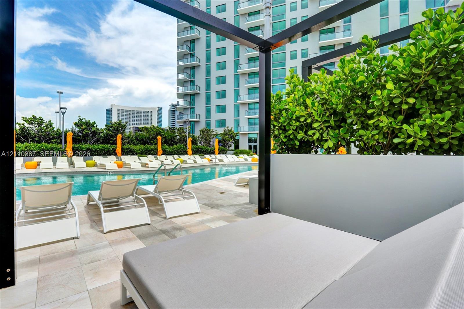 Outdoor swimming pool featuring stone-tiled decking, black metal pergola structures, and integrated privacy partitions