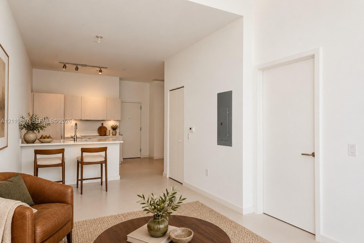 Kitchen featuring light-toned cabinetry, a peninsula with counter seating, track lighting, and solid-surface flooring Kitchen featuring light-toned cabinetry, a peninsula with counter seating, track lighting, and solid-surface flooring