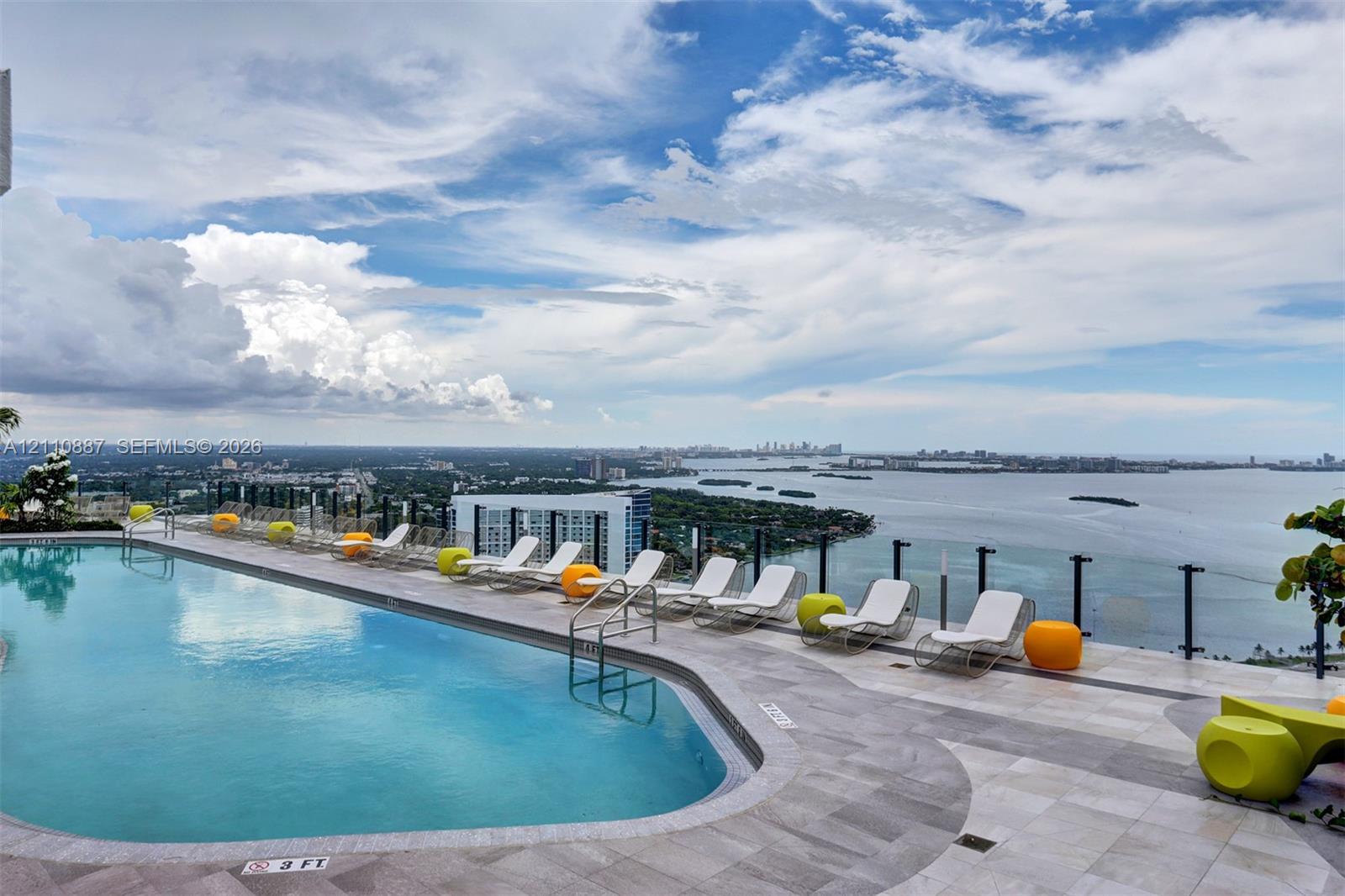 Rooftop swimming pool with stone-tiled decking and glass panel railing