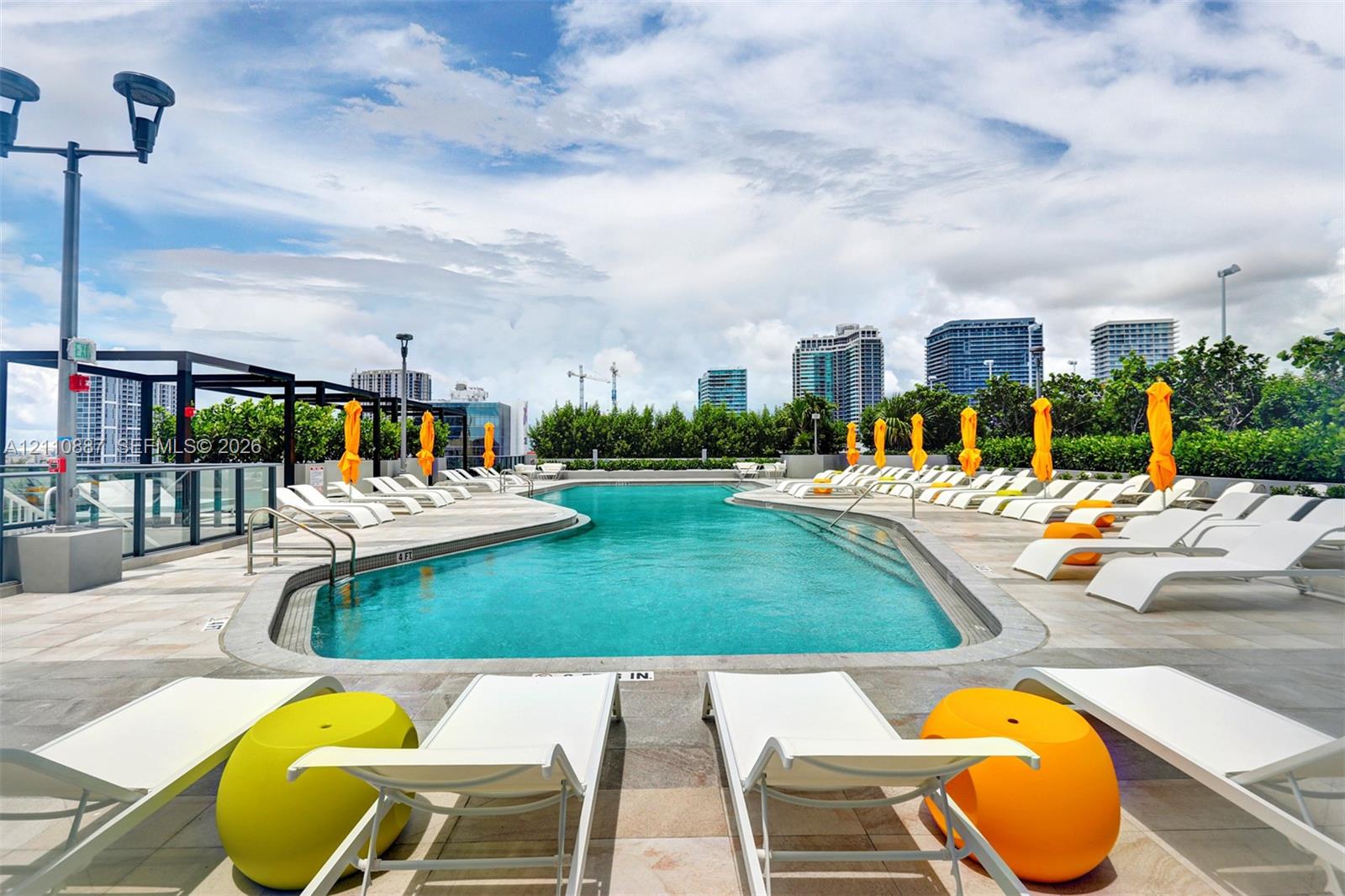 Rooftop swimming pool featuring stone deck surfacing, metal perimeter fencing, and integrated lighting fixtures