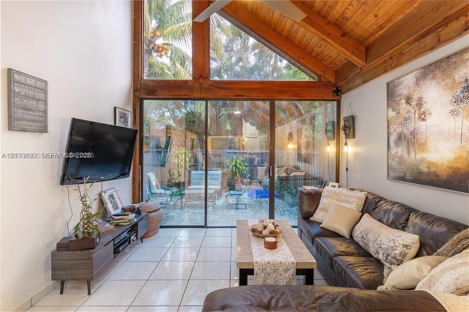 Vaulted ceiling with exposed wood beams, full-height windows, and expansive sliding glass doors