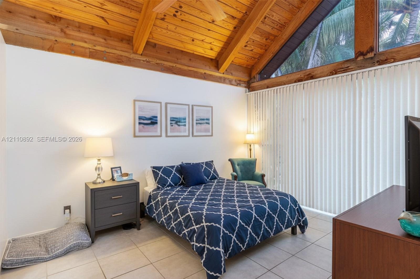 Vaulted wood-plank ceiling with exposed beams, expansive triangular clerestory windows, and large-format tile flooring