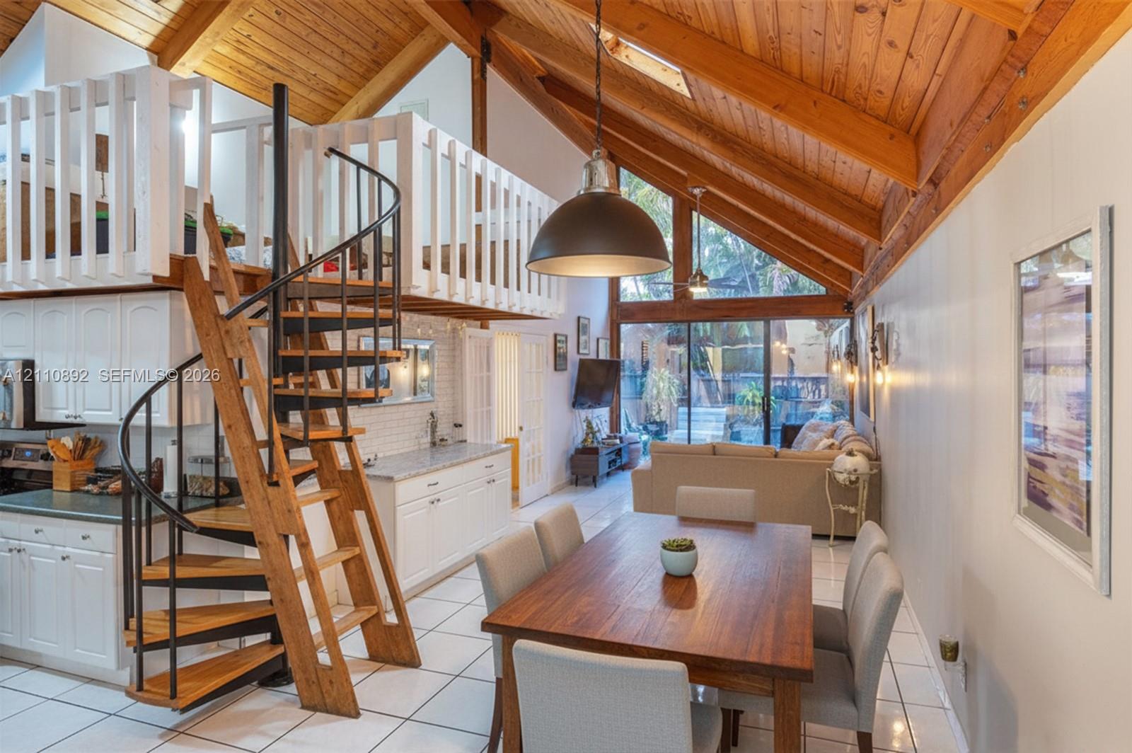 Vaulted wood-paneled ceilings, floor-to-ceiling glass paneling, white built-in cabinetry, custom metal and wood-finished spiral staircase, and lofted upper level Vaulted wood-paneled ceilings, floor-to-ceiling glass paneling, white built-in cabinetry, custom metal and wood-finished spiral staircase, and lofted upper level